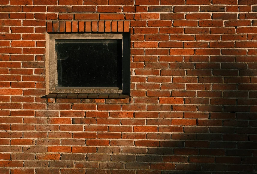 Close-up van afbrokkelende voegen rond een kozijn